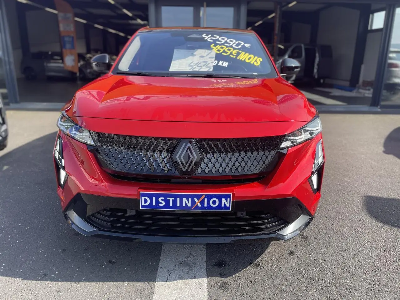 Vue frontale d'un Renault Rafale rouge à toit noir avec calandre noire et plaque Distinxion visible.
