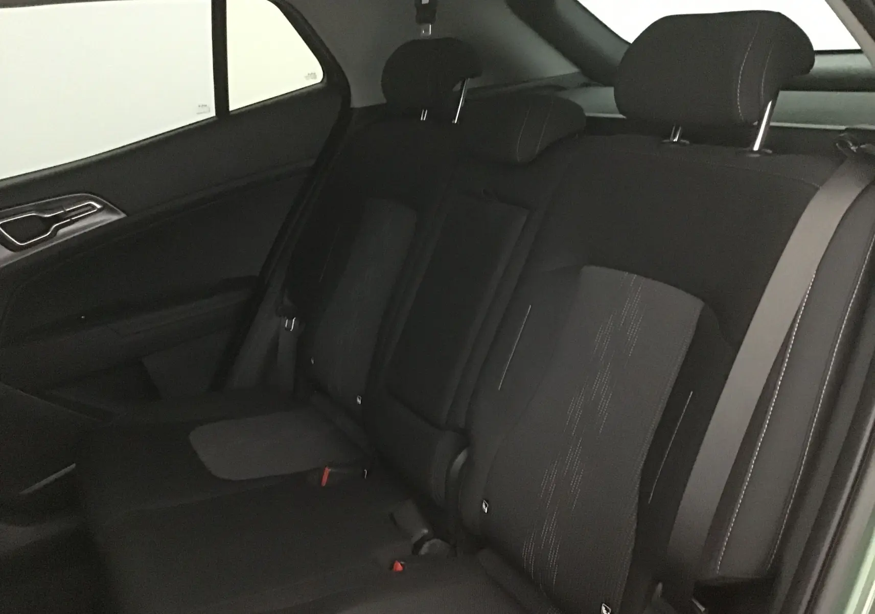 Vue intérieure du siège arrière côté droit du Kia Sportage 2025, tissu noir avec ceinture de sécurité visible.