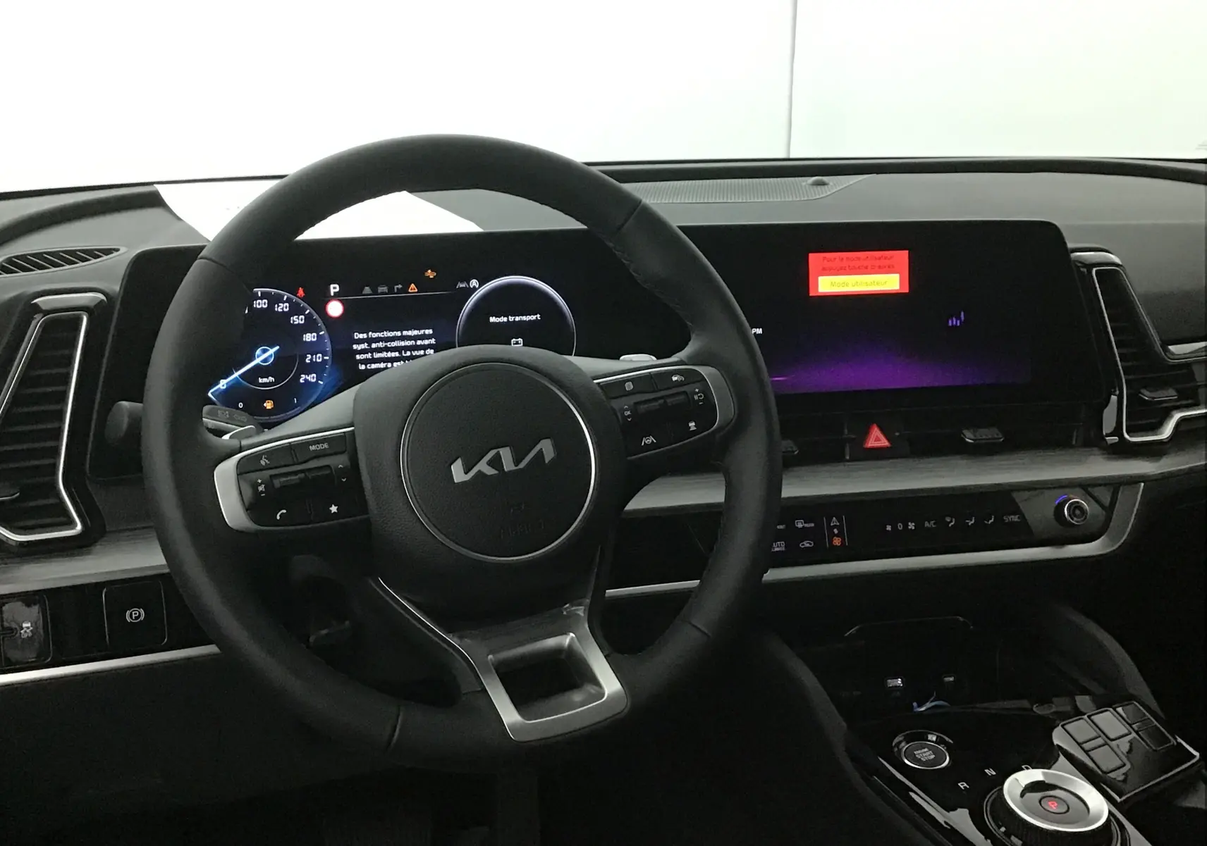 Intérieur du Kia Sportage 2025, vue du poste de conduite avec volant cuir et écran digital 12,3 pouces allumé.