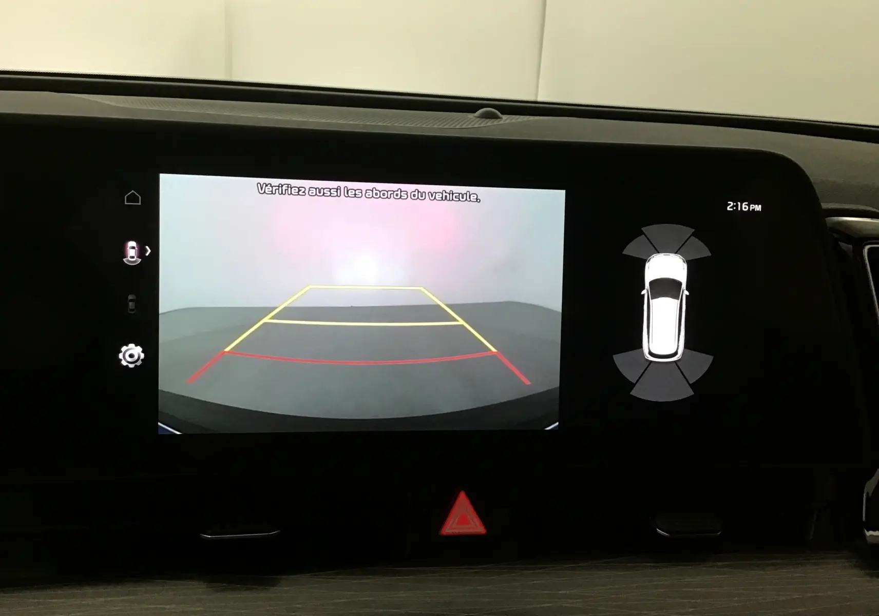 Écran digital 12,3'' du Kia Sportage 2025 montrant la caméra de recul avec lignes de guidage et capteurs d'obstacles.