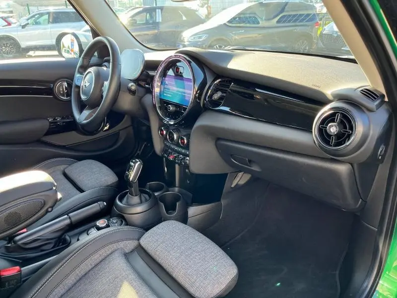 Intérieur avant droit d'une MINI Cooper S 2021 British Racing Green avec tableau de bord noir brillant et sièges gris.
