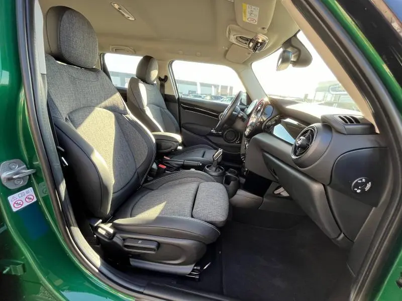 Intérieur côté conducteur d'une MINI Cooper S 2021 British Racing Green, sièges sport tissu gris et tableau de bord noir.