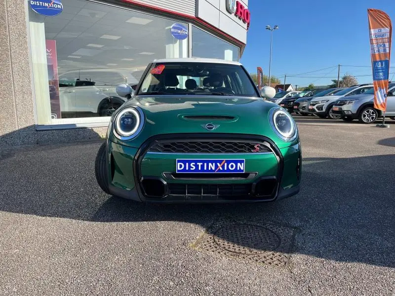 Vue frontale d'une MINI Cooper S British Racing Green avec toit blanc et phares LED circulaires allumés.