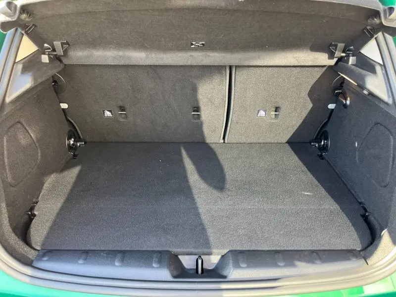 Coffre ouvert vu de face d'une MINI Cooper S 2021 British Racing Green, intérieur noir et tapis de sol propre.