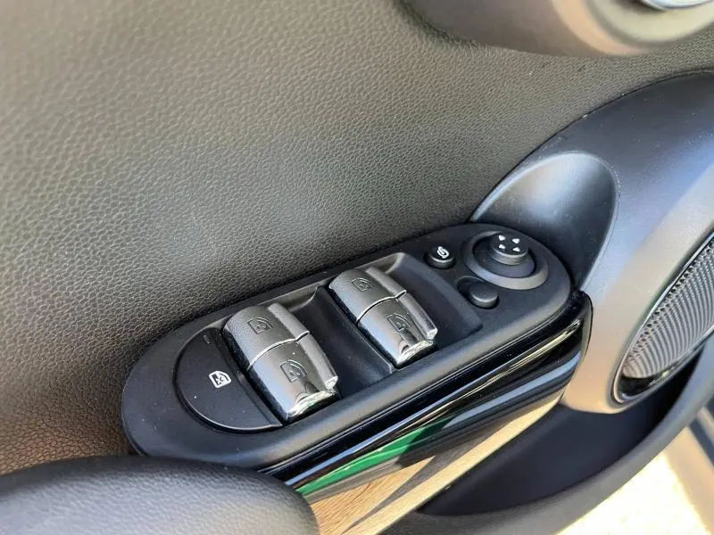 Gros plan sur les commandes de lève-vitres et rétroviseurs côté conducteur de la MINI Cooper S British Racing Green 2021.