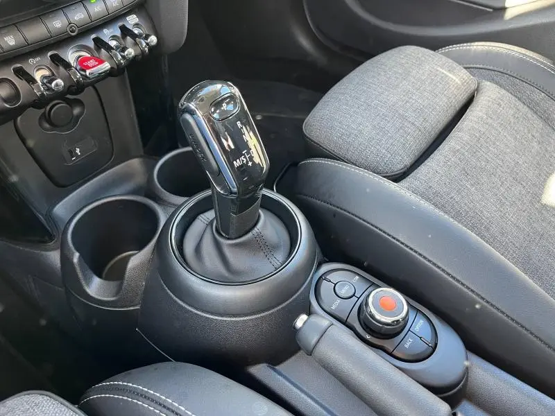 Gros plan sur la console centrale noire et grise de la MINI Cooper S 2021, avec levier de vitesse automatique et accoudoir en similicuir.