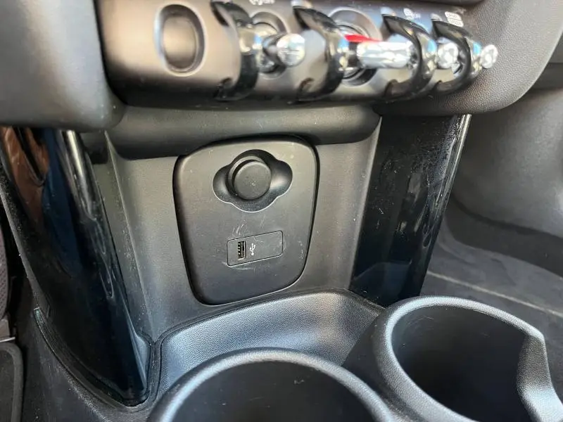 Gros plan sur la console centrale noire de la MINI Cooper S 2021, montrant prise USB et porte-gobelets.