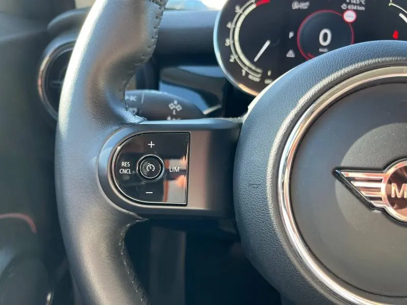 Gros plan sur le volant cuir noir de la MINI Cooper S 2021, avec commandes de régulateur de vitesse à gauche.