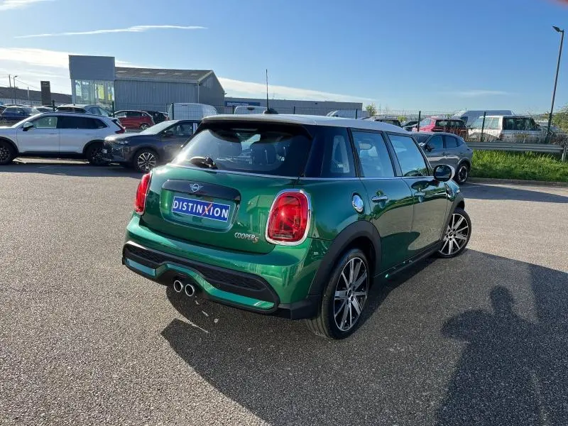 Vue 3/4 arrière droite d'une MINI Cooper S 2021 British Racing Green avec toit blanc et double sortie d'échappement chromée.