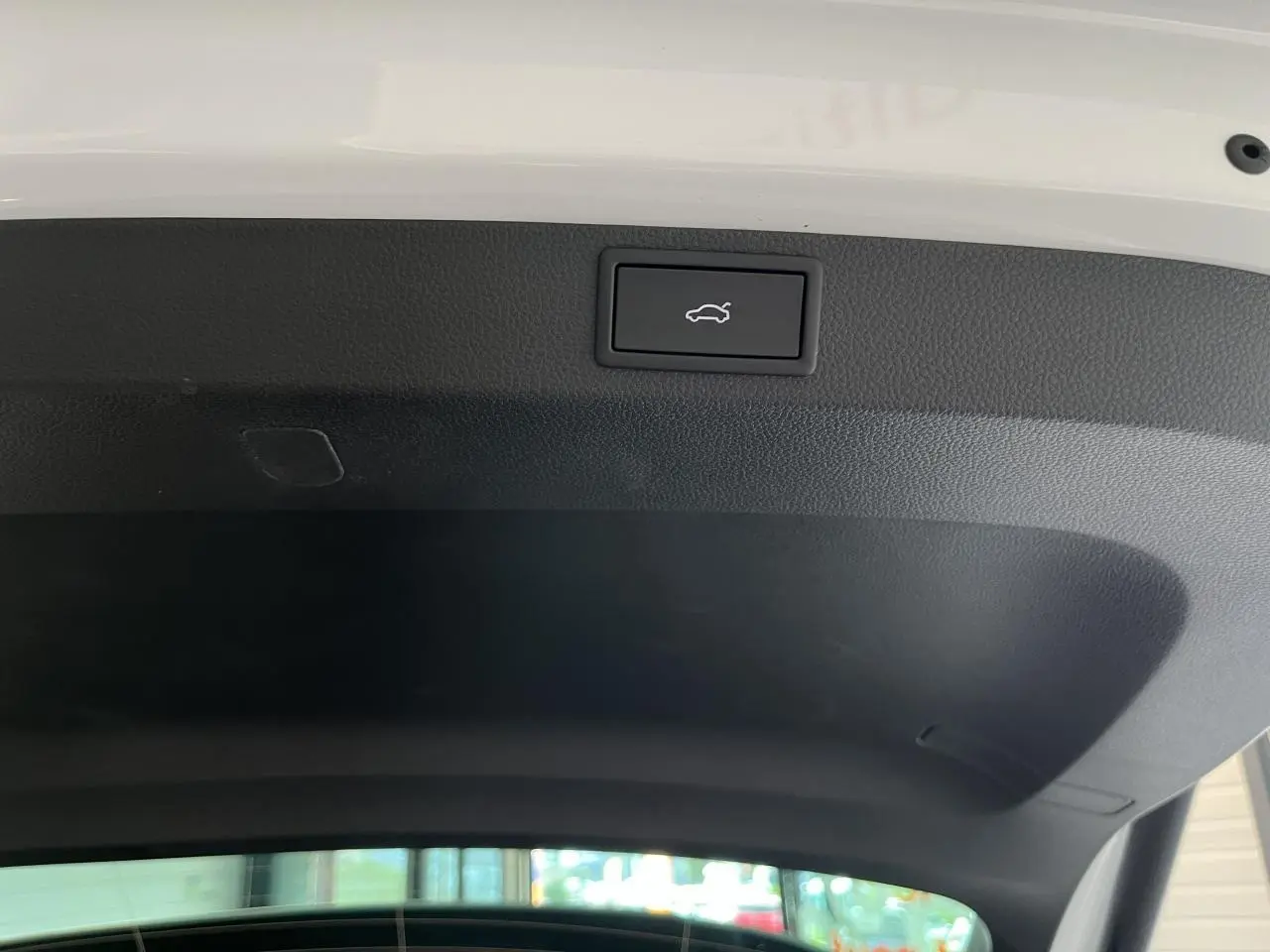 Bouton d'ouverture électrique du hayon sur la face intérieure du coffre d'un Skoda Karoq blanc.