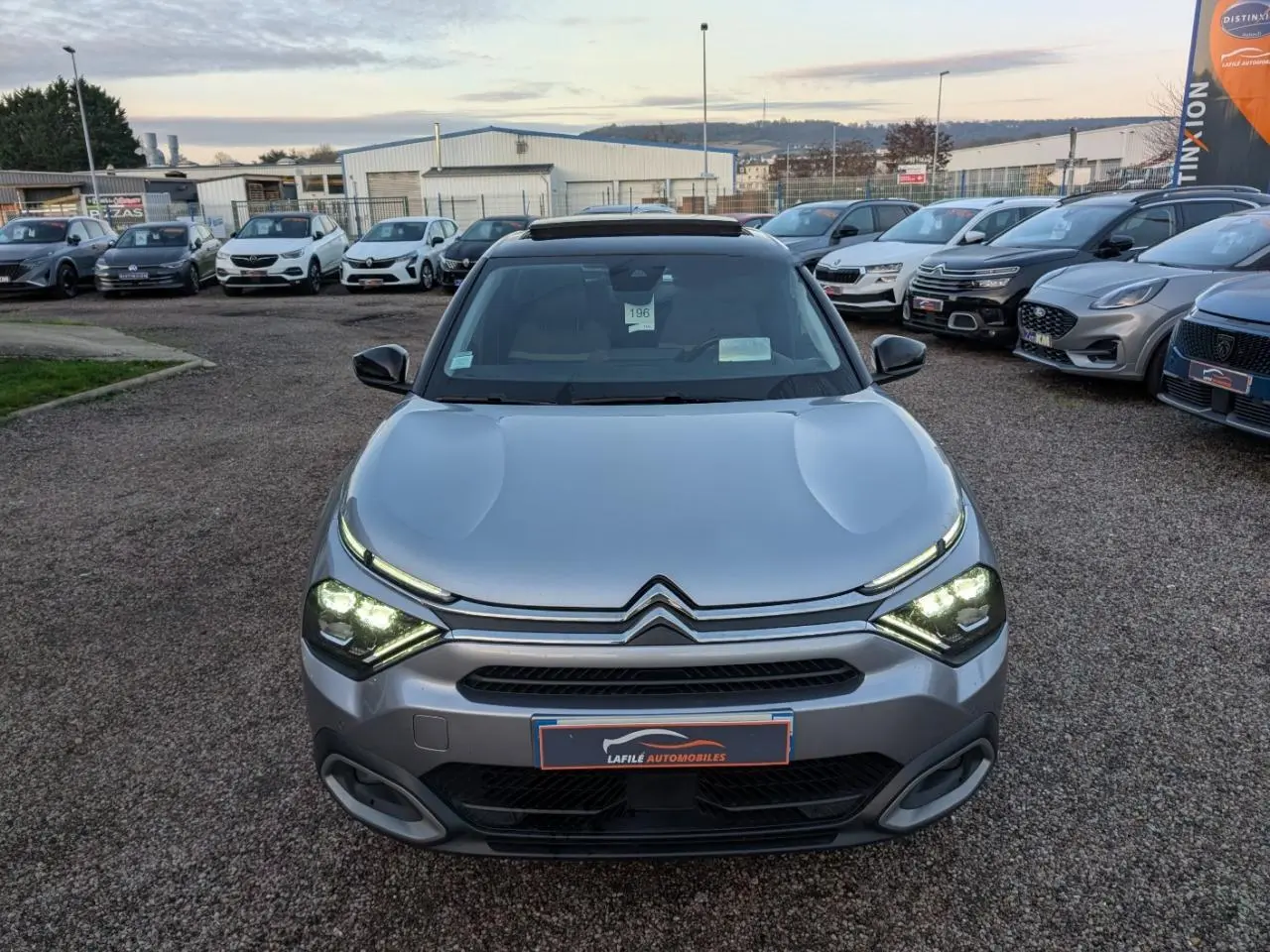 Citroën C4 gris métallisé vue de face avec phares LED allumés et toit ouvrant vitré visible.