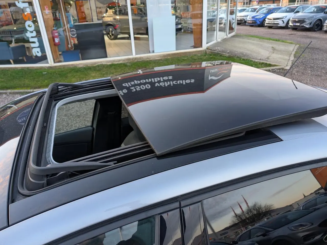 Toit ouvrant vitré ouvert vu de dessus sur une Citroën C4 gris métallisé stationnée en extérieur.