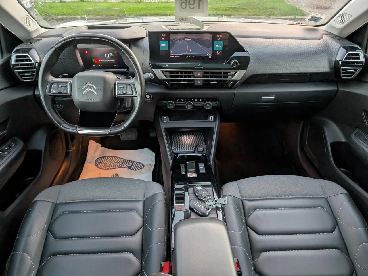Vue intérieure avant du poste de conduite de la Citroën C4 Shine 2022 avec sièges cuir noir et écran tactile central.
