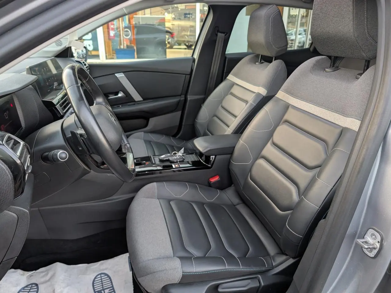 Vue intérieure côté conducteur de la Citroën C4 2022 gris, sièges Advanced Comfort cuir et textile noir, volant cuir.