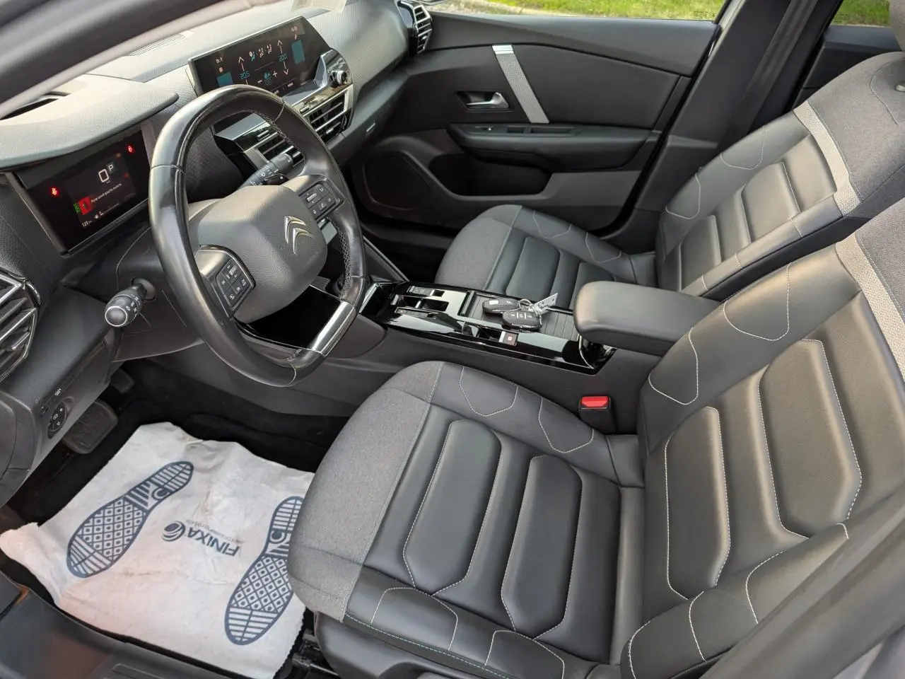 Vue intérieure côté conducteur de la Citroën C4 gris, avec sièges cuir/textile noirs et console centrale brillante.