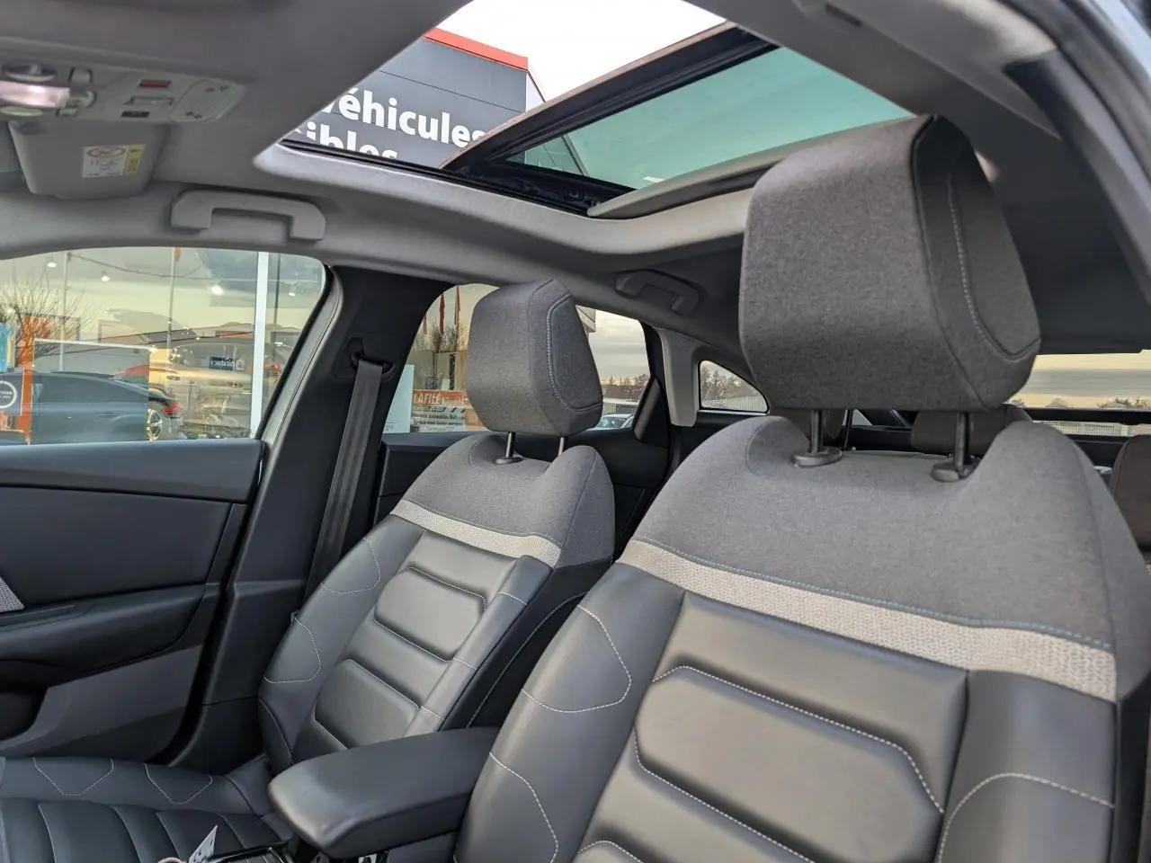 Vue intérieure avant de la Citroën C4 2022, sièges Advanced Comfort gris et toit ouvrant vitré partiellement ouvert.