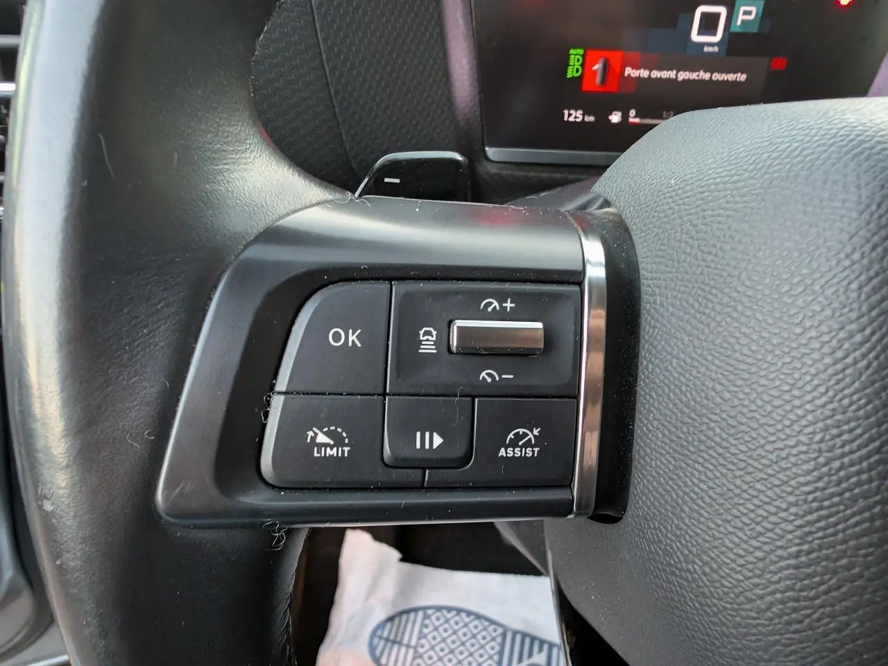 Gros plan sur les commandes au volant à gauche de la Citroën C4 2022, avec affichage numérique en arrière-plan.