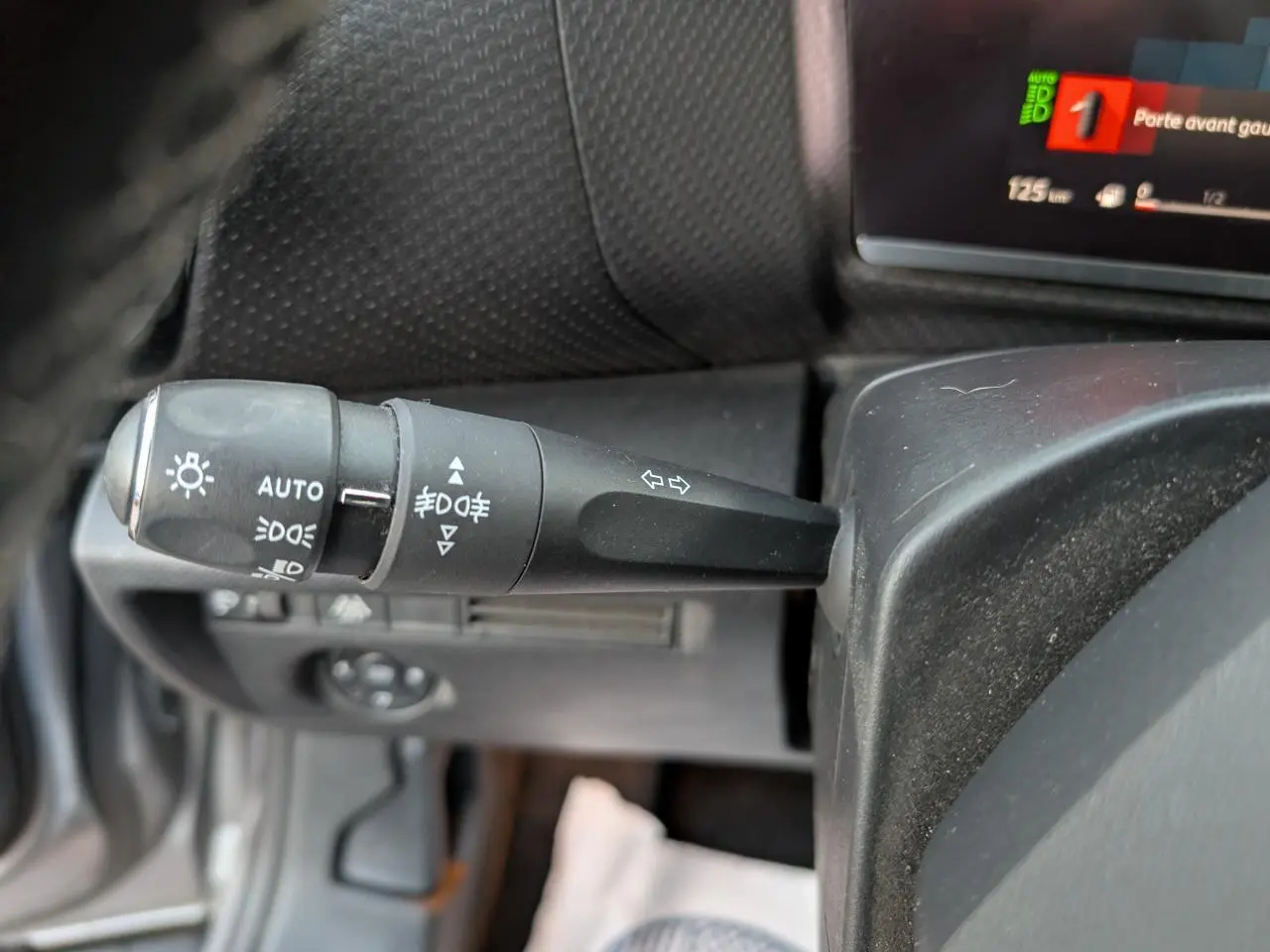 Gros plan sur la manette de clignotants et feux à gauche du volant dans l’habitacle du Citroën C4 gris 2022.