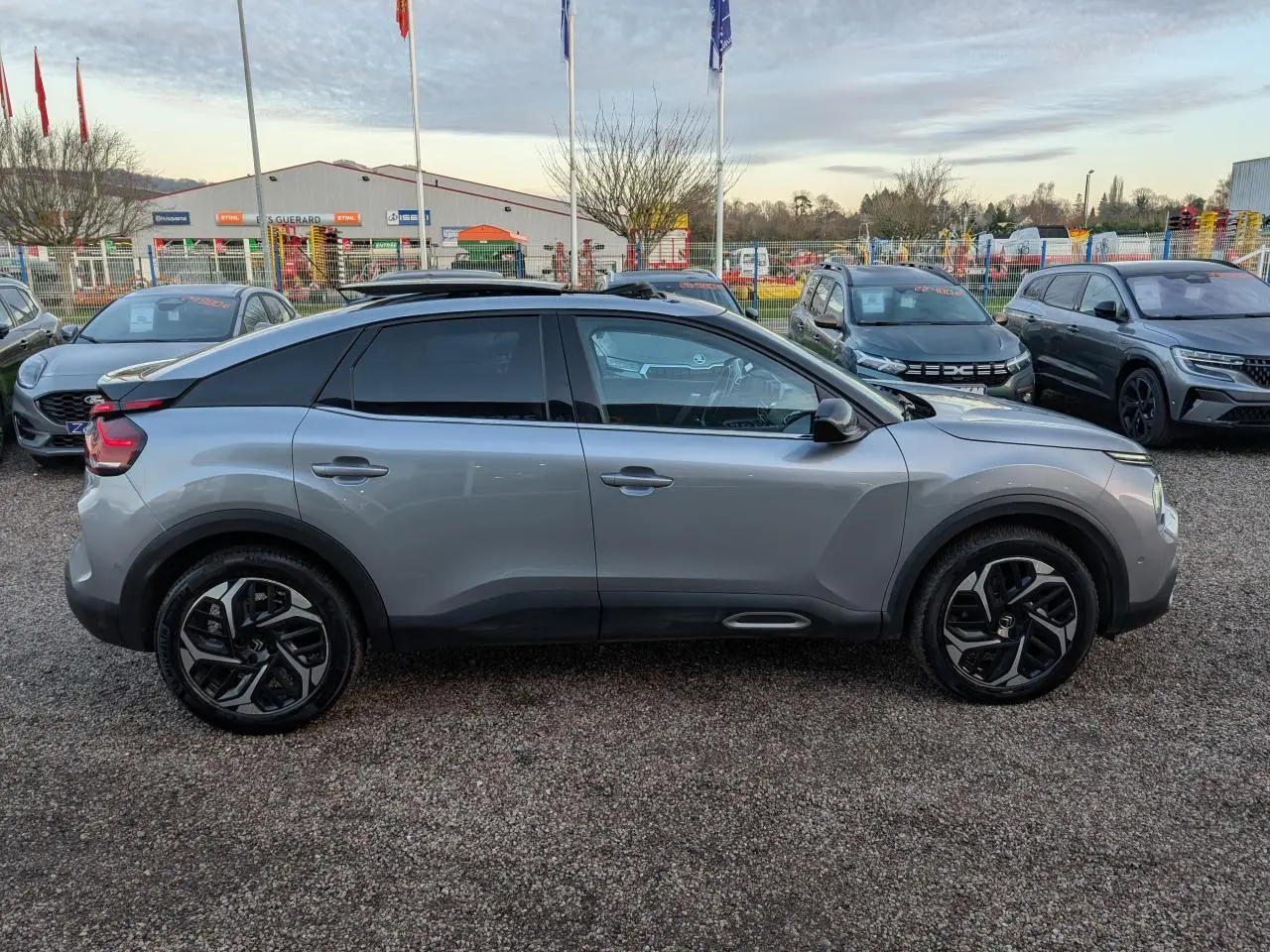 Profil côté gauche d'une Citroën C4 gris métallisé 2022 avec toit ouvrant et jantes alliage noires.
