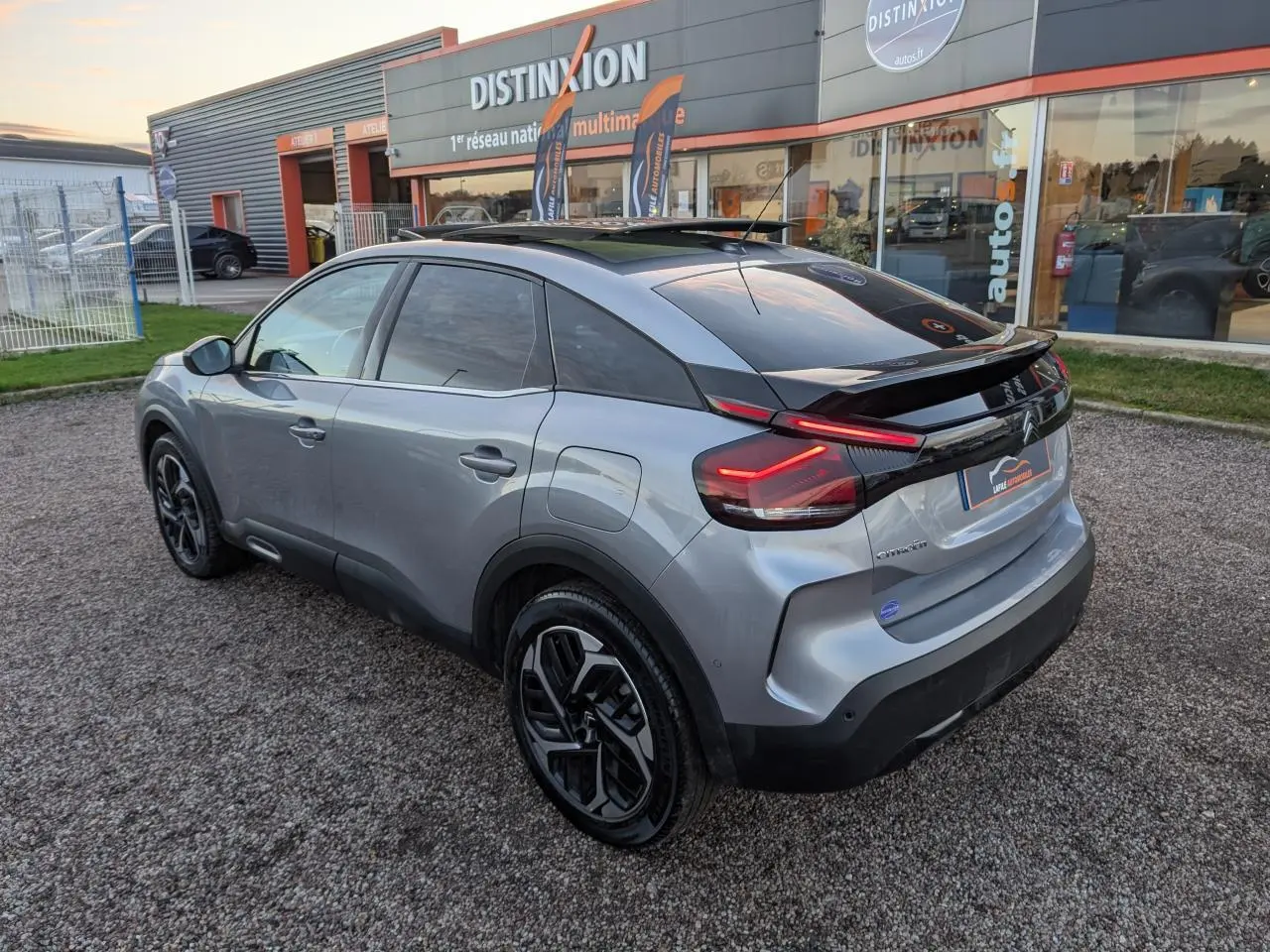 Citroën C4 gris métallisé vue 3/4 arrière droit avec toit ouvrant vitré et jantes alliage 18 pouces.