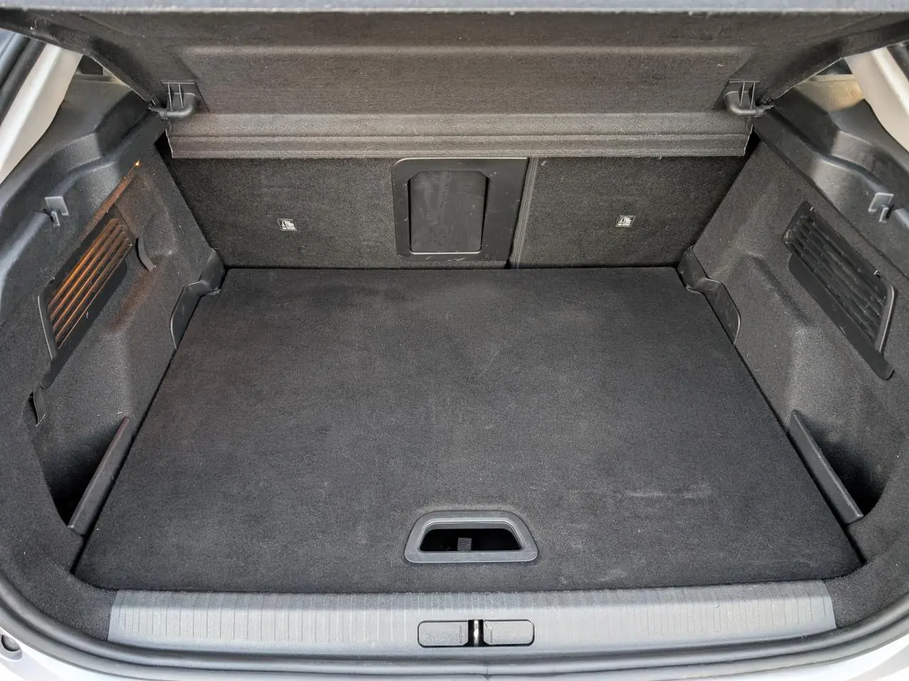 Coffre ouvert vu de l'arrière d'une Citroën C4 gris, avec plancher plat et trappe à skis intégrée.