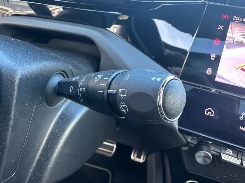 Gros plan sur la commande des essuie-glaces à gauche du volant dans l’habitacle gris d’une Peugeot 308 2022.