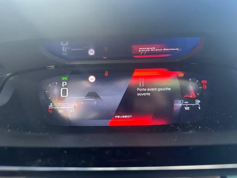 Tableau de bord numérique de Peugeot 308 gris Artense, affichant porte avant gauche ouverte et indicateurs de vitesse et carburant.