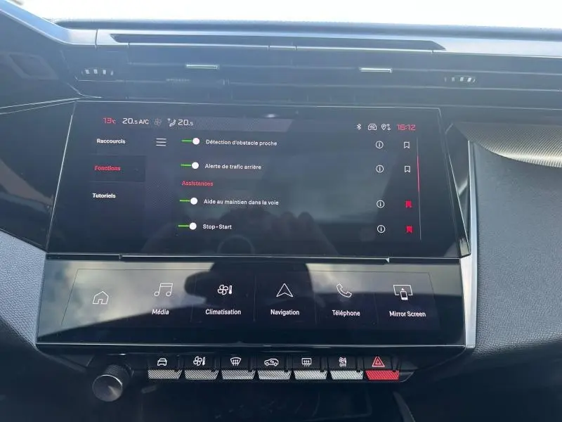 Vue rapprochée de l'écran tactile central et de la console de la Peugeot 308 gris Artense, affichant les aides à la conduite.