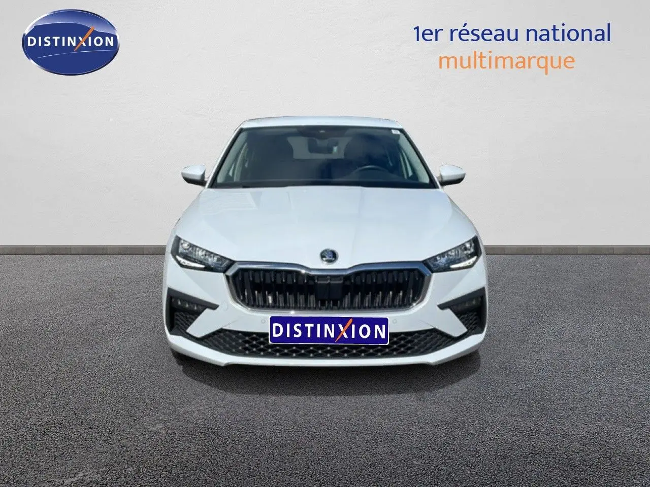 Vue avant d'une Skoda Scala blanc glacier avec calandre noire et phares LED, stationnée sur sol gris.