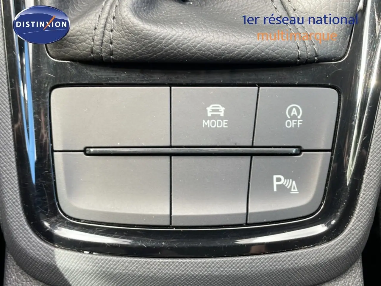 Gros plan sur les boutons de commande du mode de conduite et de l’aide au stationnement dans une Skoda Scala blanche Glacier 2025.