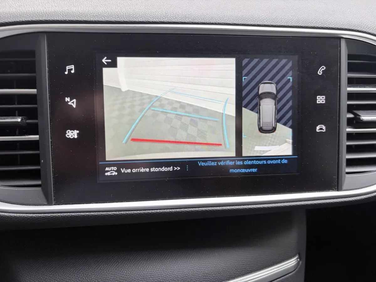 Écran tactile central affichant la caméra de recul et l’aide au stationnement du Peugeot 308 gris foncé, vue intérieure.