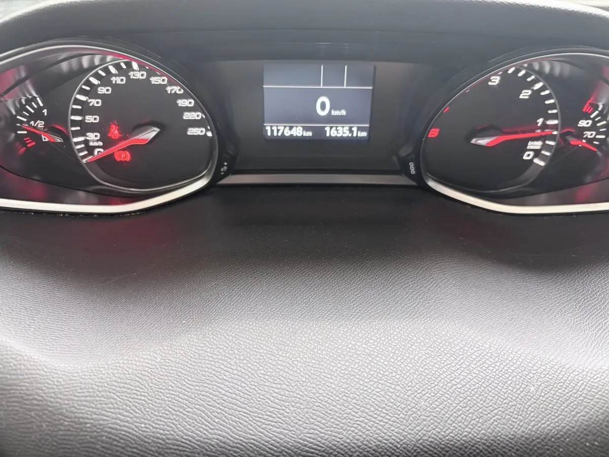 Vue rapprochée du tableau de bord de la Peugeot 308 gris foncé, affichage digital et compteurs analogiques rouges.