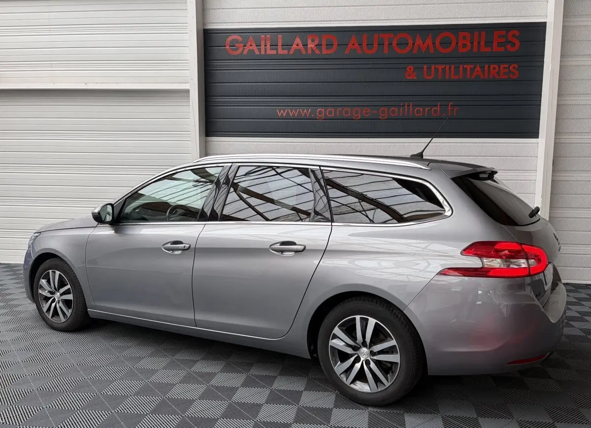 Peugeot 308 BlueHDi 130 gris foncé en profil droit, break avec vitres teintées et jantes alliage.