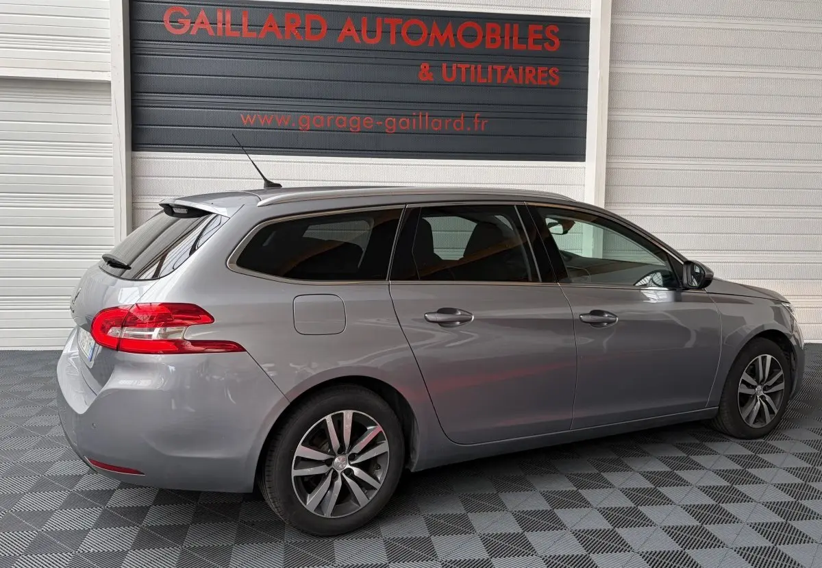 Peugeot 308 gris foncé vue de profil côté droit, break avec feux arrière rouges et jantes alliage.