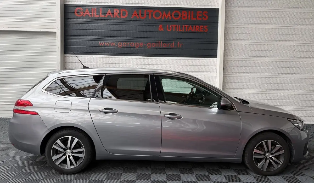 Peugeot 308 BlueHDi 130 gris foncé vue de profil côté gauche, avec jantes alliage et vitres teintées.