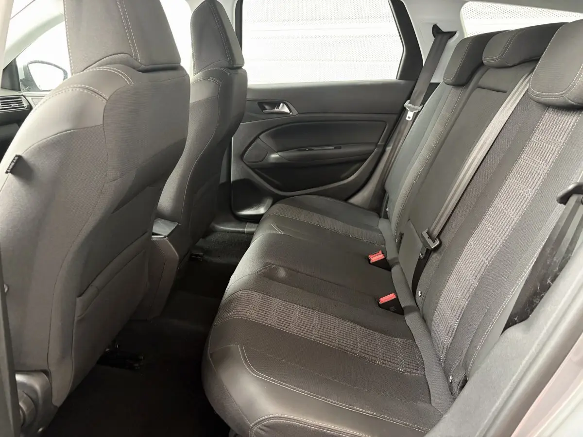 Vue latérale intérieure montrant la banquette arrière noire et les dossiers des sièges avant d'une Peugeot 308 gris foncé.