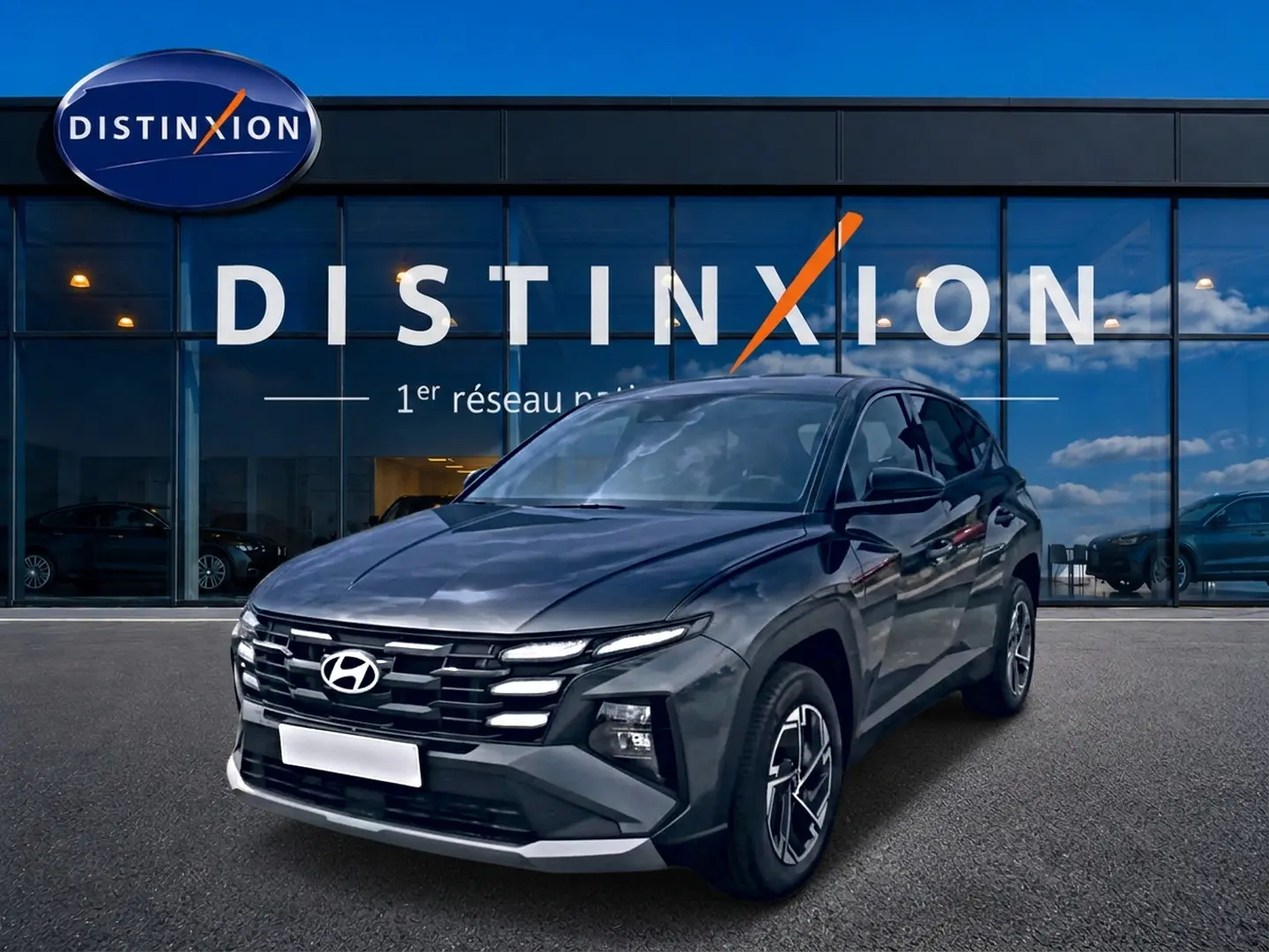 Hyundai Tucson 1.6 t-gdi 239 hybride gris ecotronique en 3/4 avant droit devant une vitrine Distinxion.
