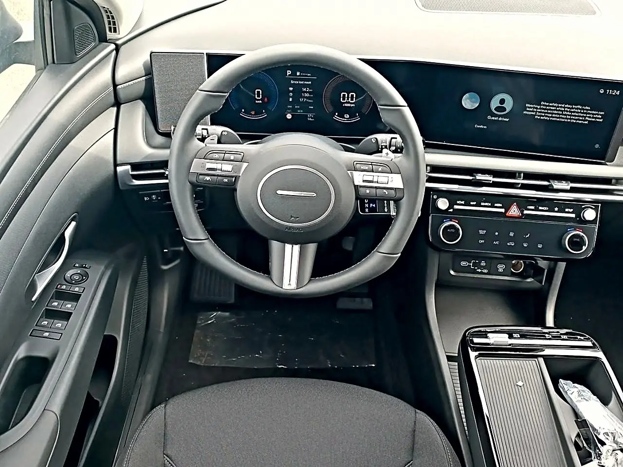 Vue intérieure frontale du tableau de bord et volant cuir multifonctions du Hyundai Tucson 2026, finition hybride, avec écran large numérique.