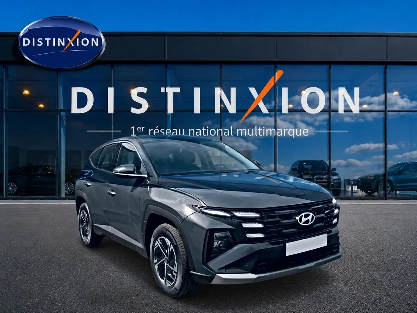 Hyundai Tucson 2026 gris ecotronique en 3/4 avant droit devant vitrine Distinxion, jantes alliage 17 pouces.