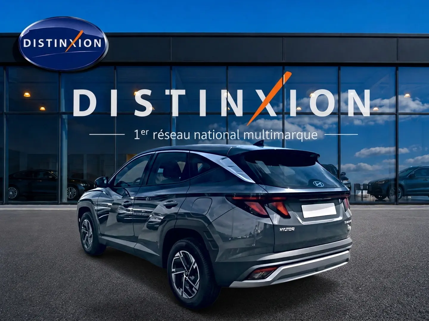 Vue 3/4 arrière droite du Hyundai Tucson gris ecotronique avec jantes alliage et feux arrière LED, devant une vitrine Distinxion.