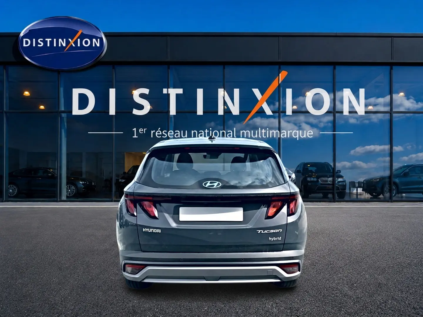 Vue arrière d'un Hyundai Tucson gris ecotronique hybride stationné devant une vitrine Distinxion.