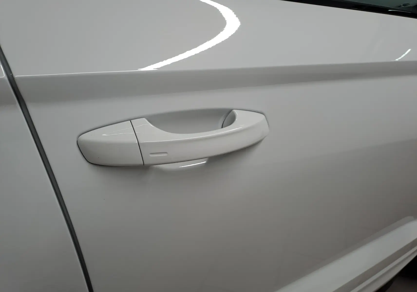 Poignée de porte côté gauche en blanc lune sur Skoda Karoq 2025, finition Sportline avec surface lisse et intégrée.