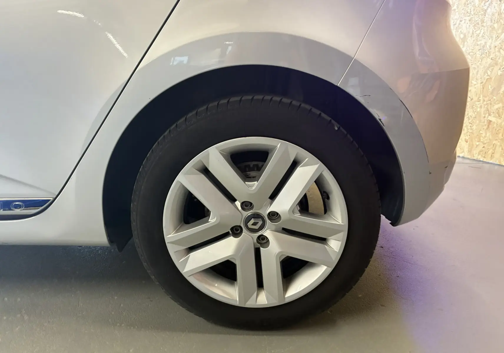 Gros plan sur la roue arrière droite d'une Renault Clio gris 2022 avec jante alliage et logo au centre.