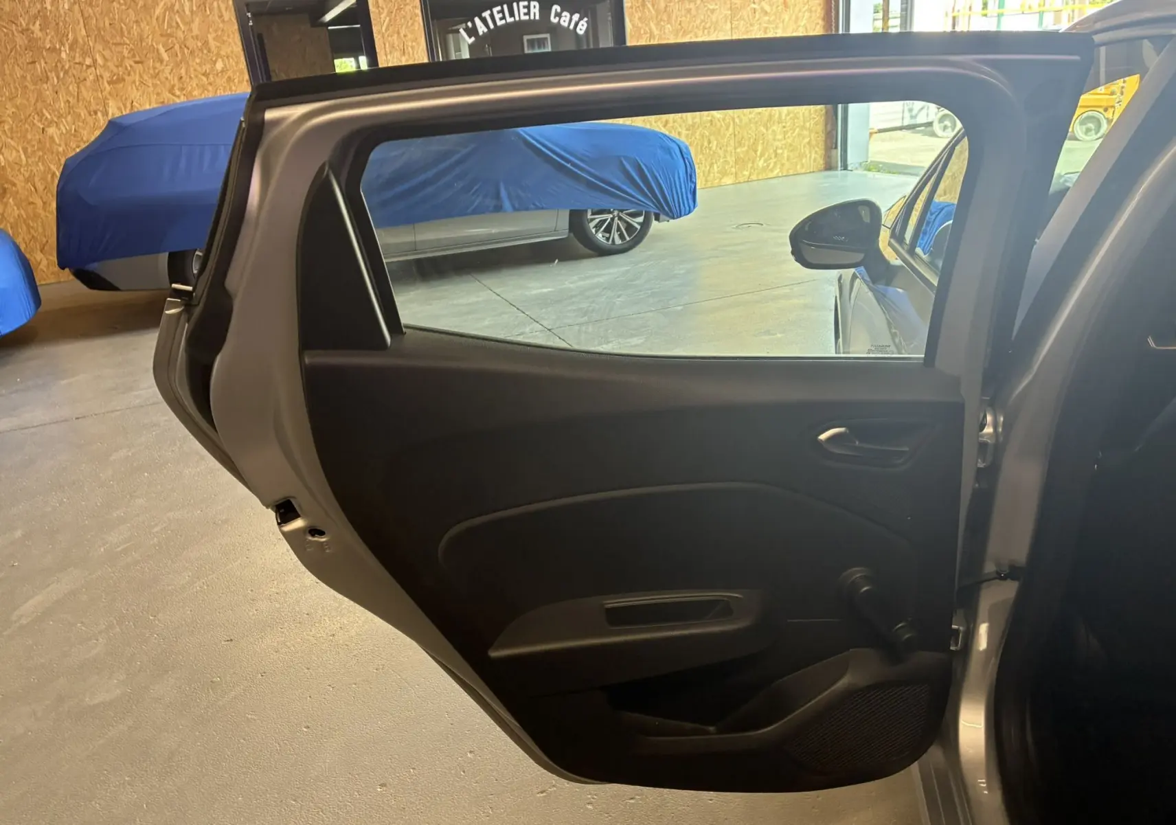 Porte arrière gauche ouverte d'une Renault Clio 1.5 BlueDCI Business gris 2022, intérieur noir en tissu visible.