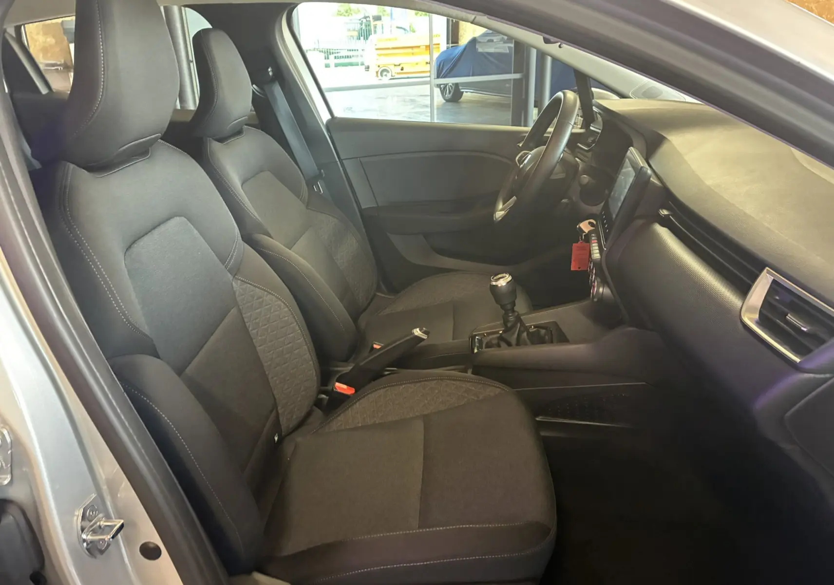 Intérieur noir de la Renault Clio 1.5 BlueDCI Business 2022, vue côté conducteur avec sièges tissu et boîte manuelle.