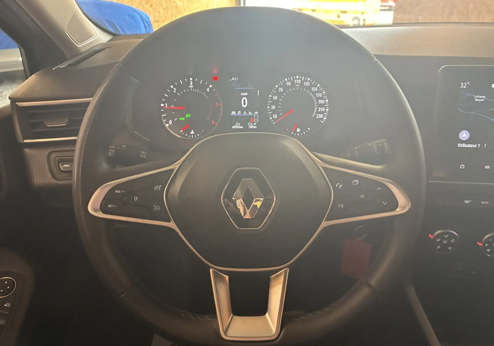 Vue rapprochée du volant noir de la Renault Clio 1.5 BlueDCI Business 2022 avec tableau de bord et commandes visibles.