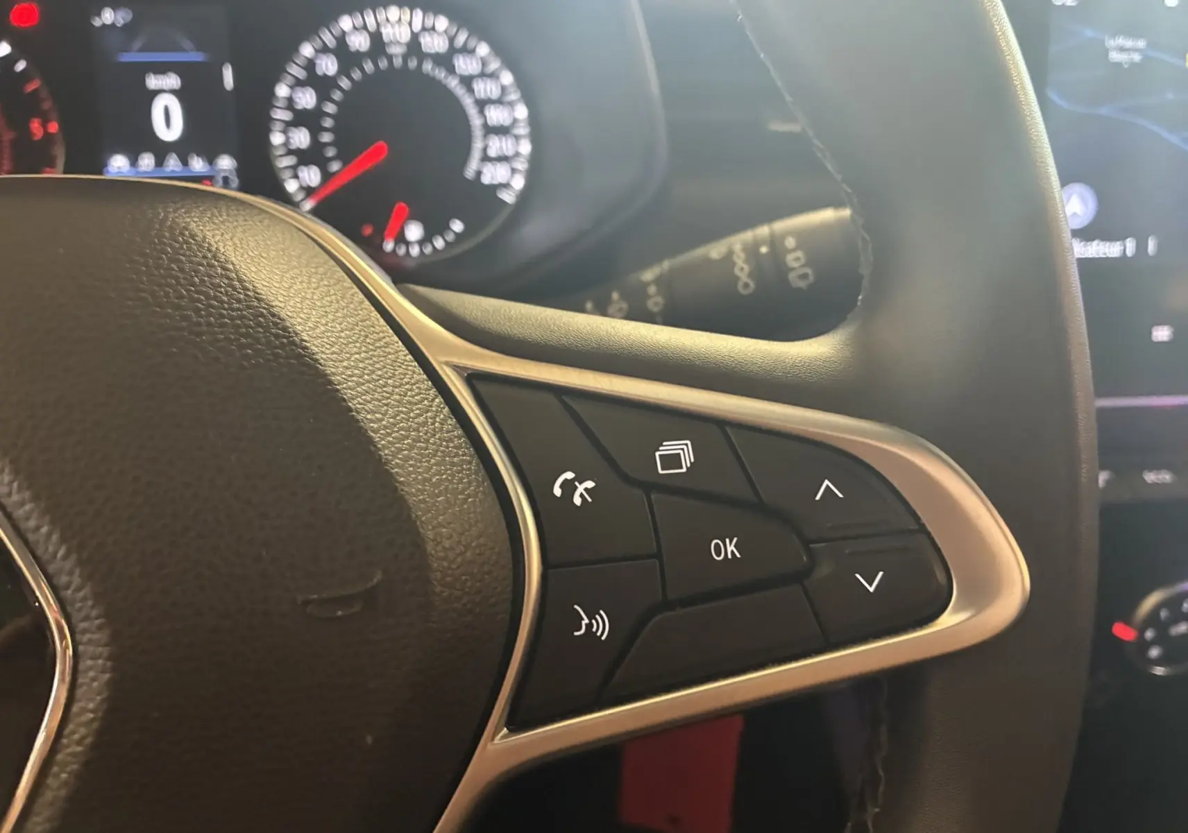 Gros plan sur les commandes au volant d'une Renault Clio 1.5 BlueDCI Business 2022, intérieur noir avec boutons multifonctions.