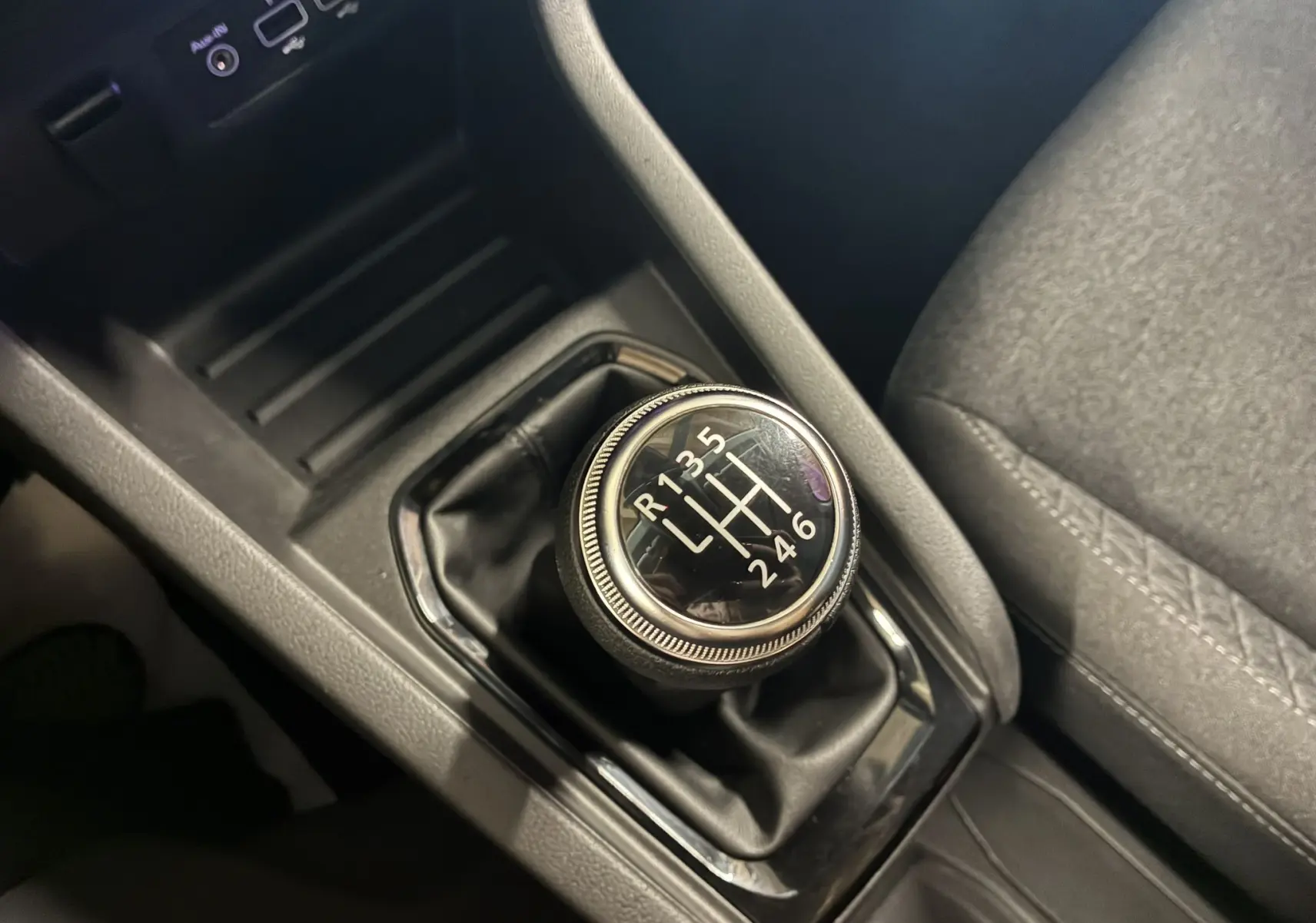 Gros plan sur le levier de vitesses manuel noir de la Renault Clio 1.5 BlueDCI Business 2022 avec intérieur tissu gris.