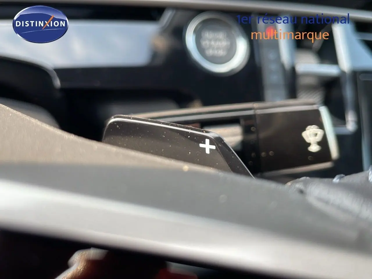 Gros plan sur la palette de changement de vitesses "+" du volant dans l'habitacle du Peugeot 3008 gris 2025.