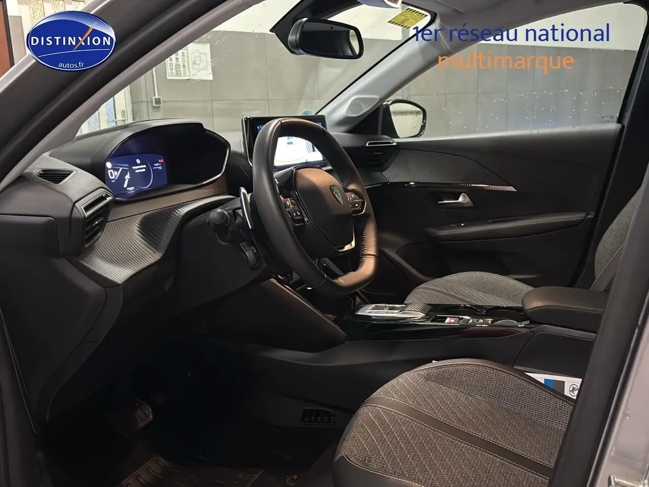 Vue intérieure côté conducteur de la Peugeot 208 1.2 hybrid 110 allure e-dcs6 avec tableau de bord numérique et sièges gris.
